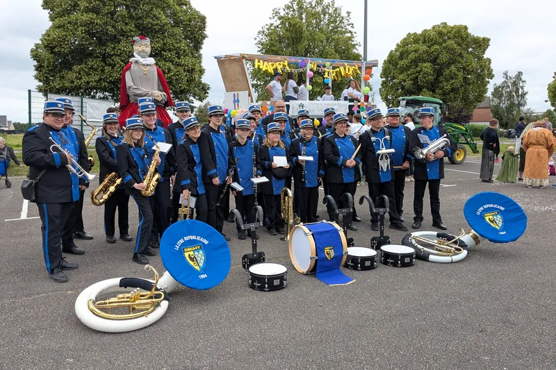 Vue large des musiciens de l'harmonie, saxophones, clarinettes et cuivres en main.